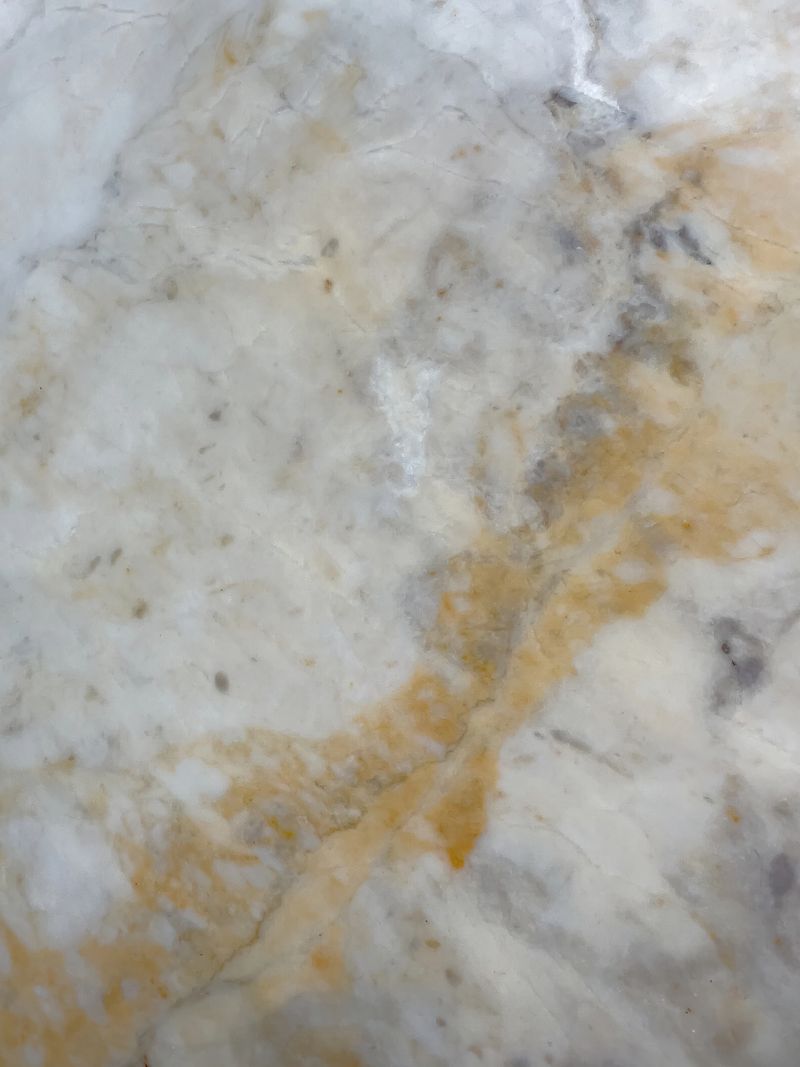 A close-up of a luxurious white marble surface with intricate golden and gray veins. The organic pattern showcases natural beauty, making this image ideal for backgrounds, interior design, architecture, and branding projects. Perfect for elegant and modern aesthetics.
