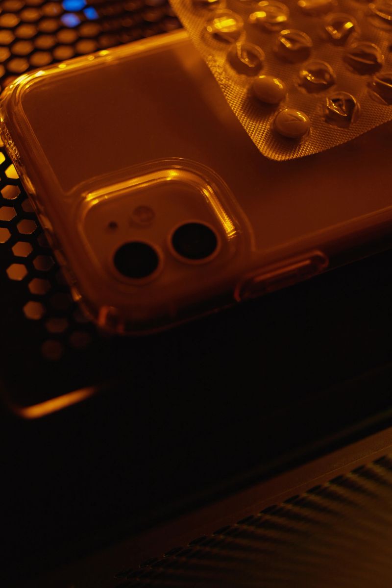 Smartphone and pills in packaging at night on a technological table with neon lights.