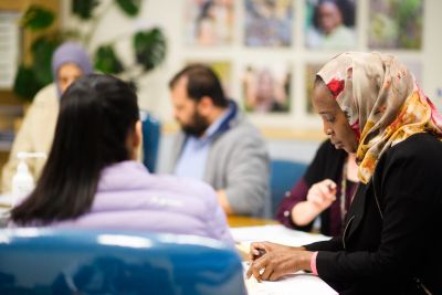 A community health education session, with a woman in a headscarf taking notes