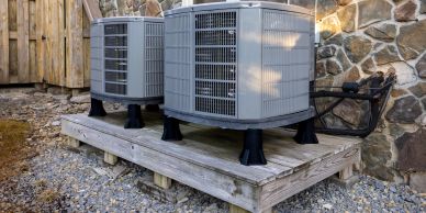 Two outdoor air conditioning units installed on a wooden platform.