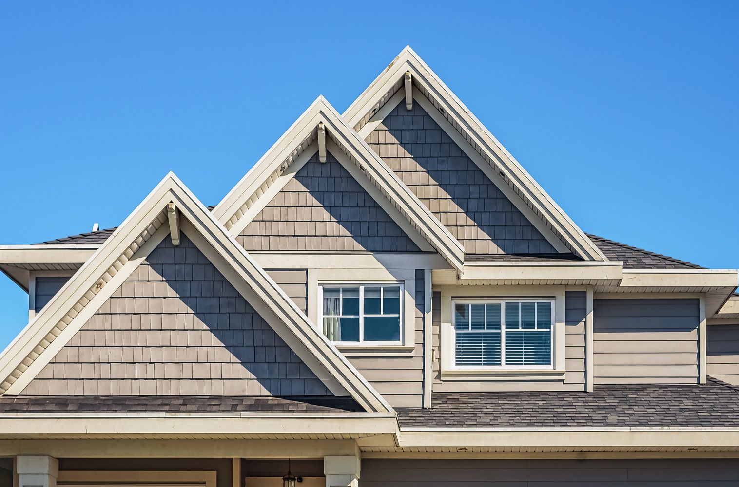 Modern house with multiple gabled roofs against a clear blue sky.