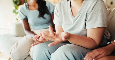 People sitting and talking, one person expressing with hand gestures.