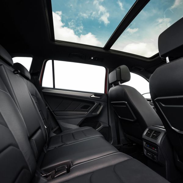 Car interior with black leather seats and panoramic sunroof.