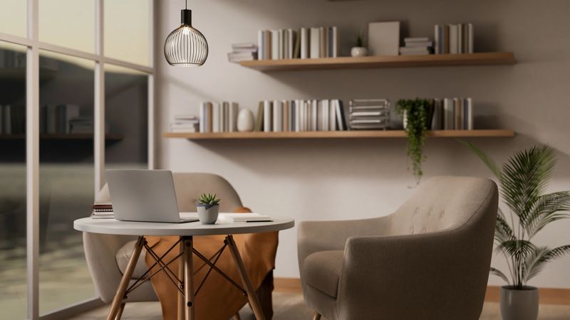 A laptop on round stool table and armchairs beside a large glass wall in the living room or cafe corner. Cosy Interior. 3D rendering, 3d illustration.