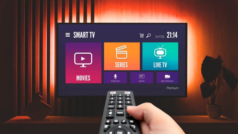 Man watching TV, remote control in hand. VOD service on TV