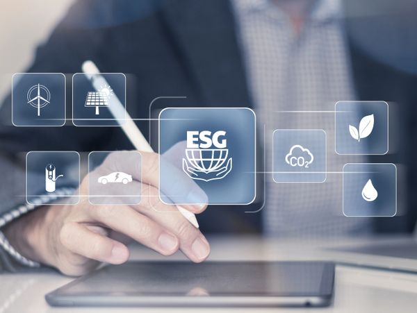 Person using a tablet with ESG and renewable energy icons floating above.