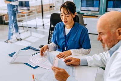 Two medical professionals reviewing patient charts in a modern office.