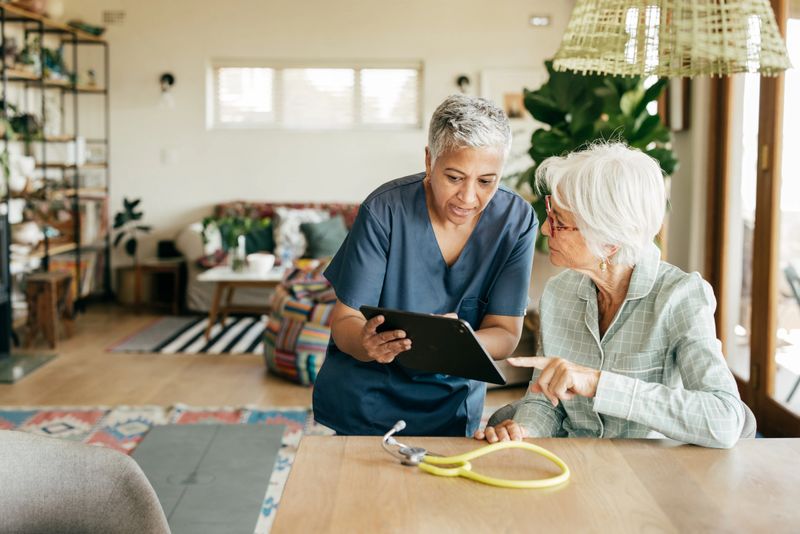 Home caregiver explaining health details to a senior woman in a cozy living room.