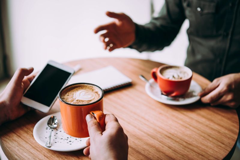 Two persons discussing business projects in a cafe while having coffee. Startup, ideas and brain storm concept
