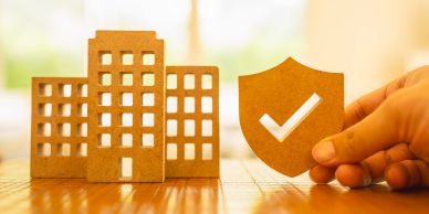 Cardboard buildings and shield with checkmark.