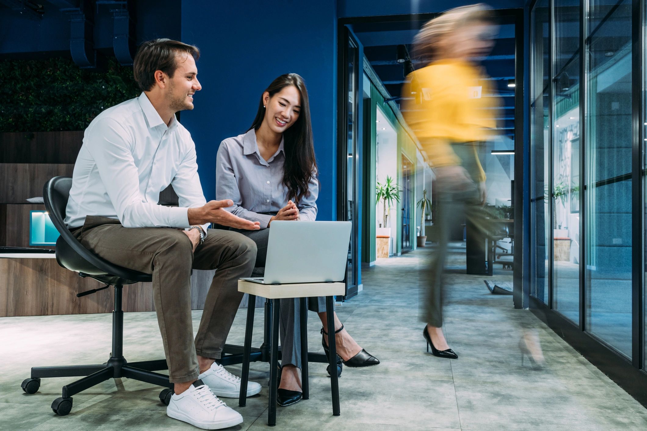 A diverse group engaged in a lively office meeting around a table.