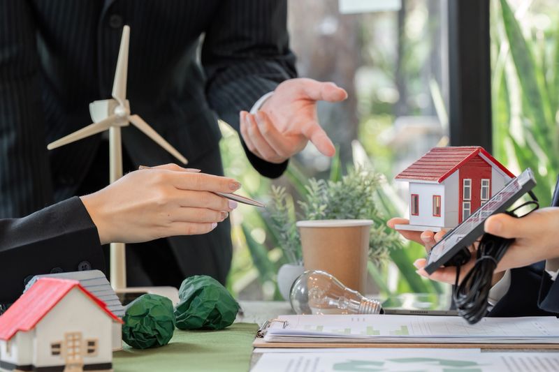 In a strategic meeting, professionals discuss eco-friendly models, including solar panels and energy-efficient housing, highlighting collaboration for sustainability.