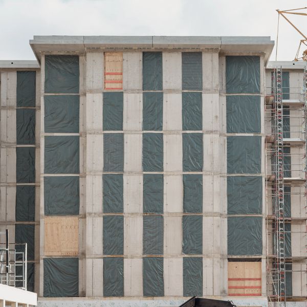 Unfinished building facade with windows covered in protective plastic sheets.