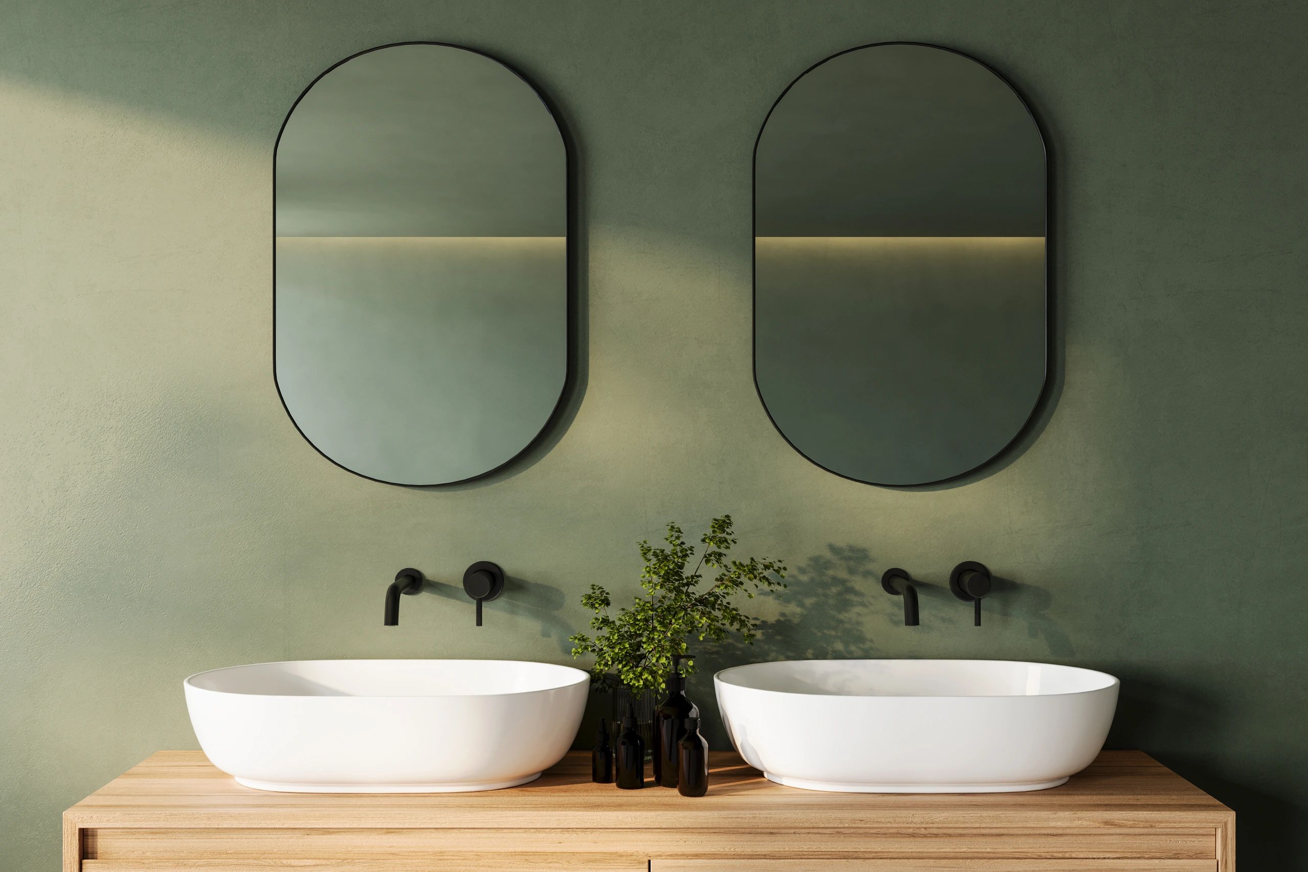 Minimalist bathroom with double sinks and oval mirrors.