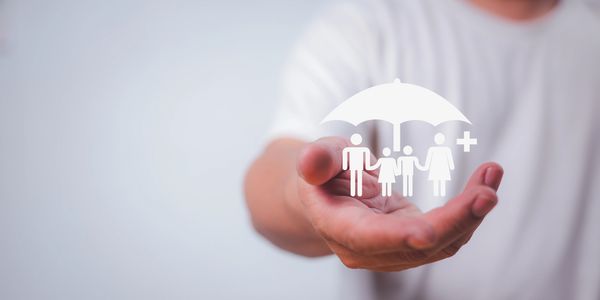 Hand holding digital family insurance icon under protective umbrella.