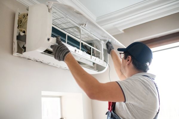 Hand adjusting a modern digital thermostat set to 66°F in eco mode.