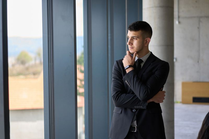 A close up portrait of a company director in a black suit, standing confidently in a modern office, exuding leadership, professionalism, and authority