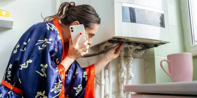 Woman inspecting a boiler while on the phone.