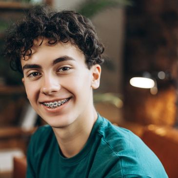 Teen patient smiling with braces as part of orthodontic treatment to straighten teeth.