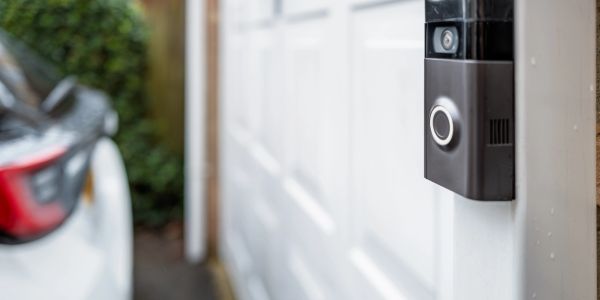 A smart doorbell installed next to a white garage door.
