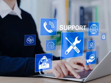Person using laptop with digital support icons floating above keyboard.