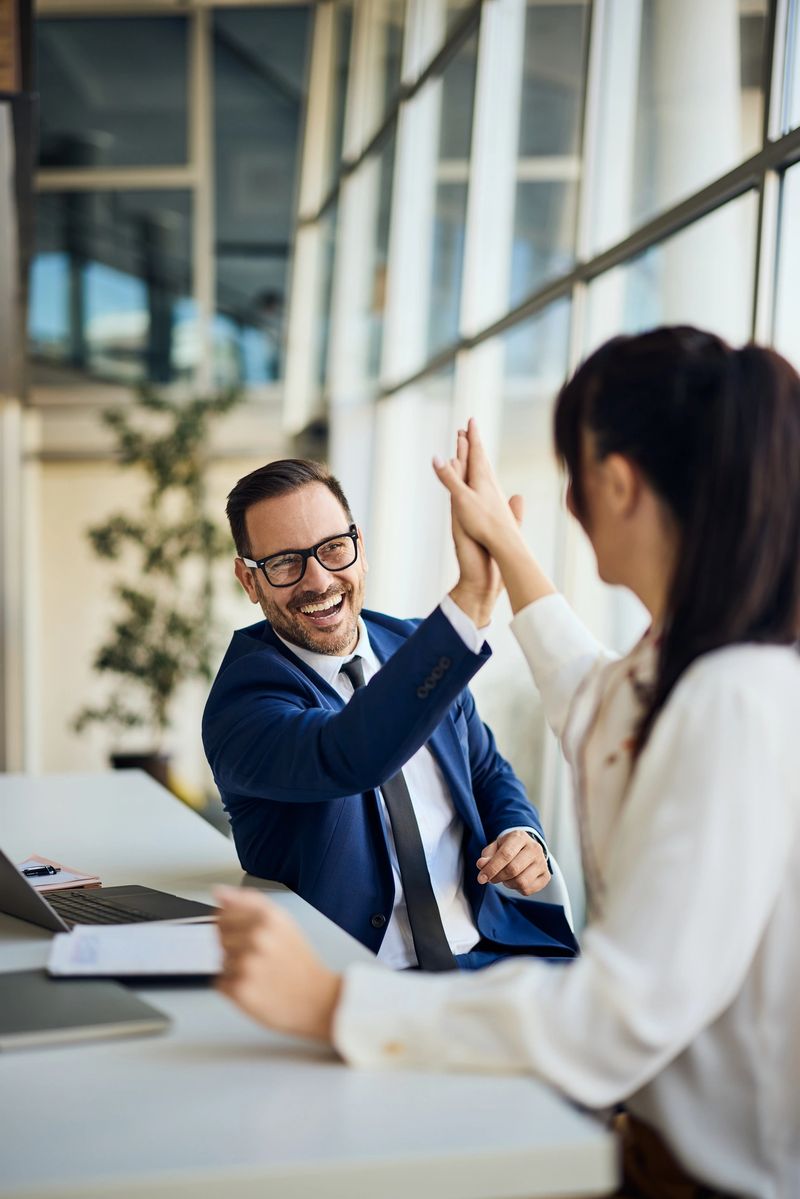 Professional coworkers enjoying teamwork and successful collaboration by exchanging a high-five.