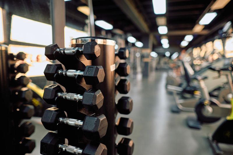 Dumbbells arranged neatly on a rack in a modern gym, highlighting essential fitness training equipment against a softly blurred background, creating a focused workout atmosphere
