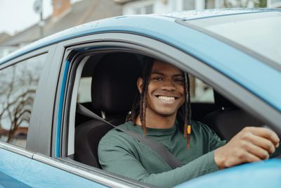 Smiling man driving a car.