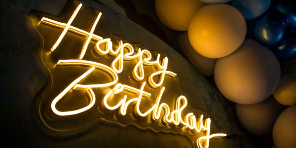 Neon sign reading 'Happy Birthday' with balloons.