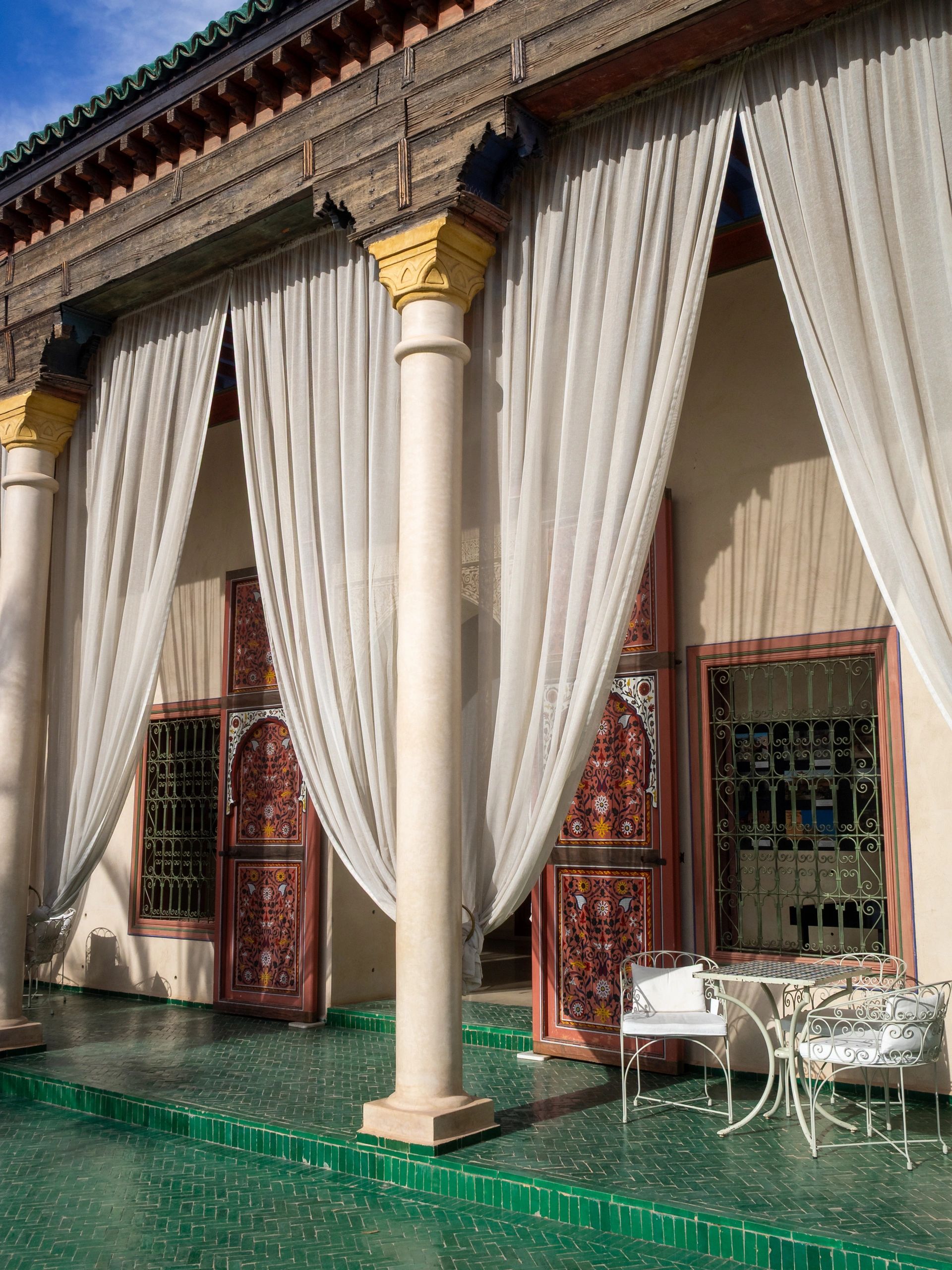 Elegant outdoor seating with sheer curtains and intricate door designs.