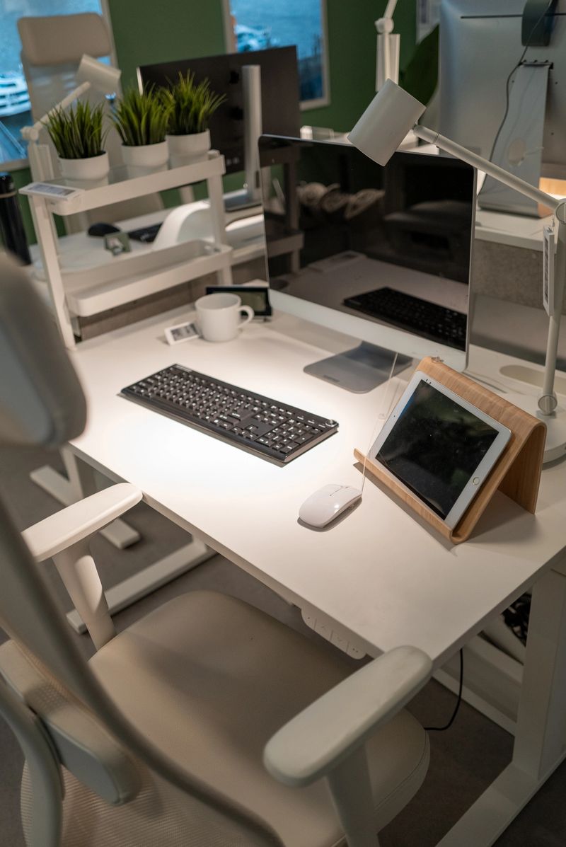 White desk in a modern office setting, featuring a computer, tablet, keyboard, and mouse, creating a productive workspace