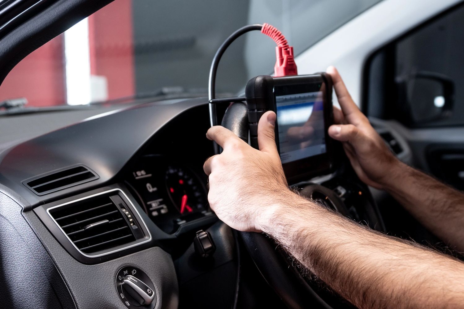 Person using a diagnostic tool on a car's steering wheel.