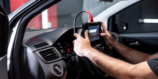 Person using a diagnostic tool inside a car.