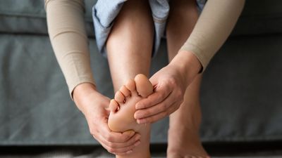 A person looking at their feet and massaging painful points.