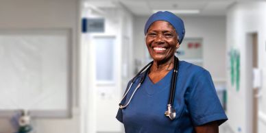Smiling nurse in blue scrubs with a stethoscope.