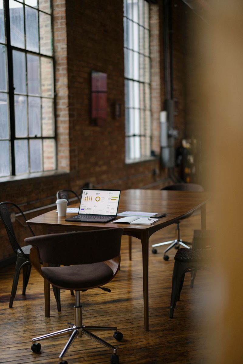 A stylish office setting featuring a wooden table, laptop with charts, and modern decor.