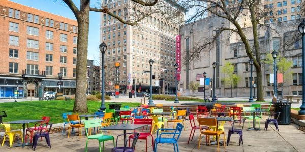 Colorful chairs and tables in an outdoor urban plaza.