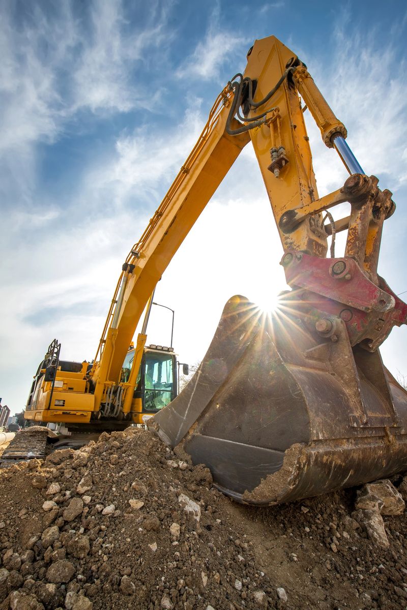 Crawler excavator during earthmoving works on construction site and sun rays