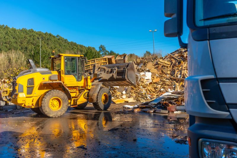 Bulldozer and truck outside a recycling plant moving waste in a sunny day