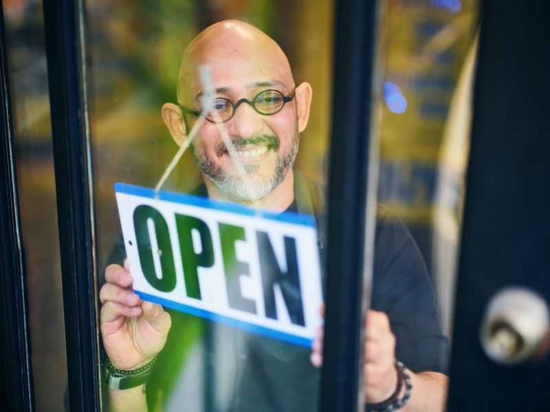 A downtown small store owner turning the sign to OPEN at the start of the day.