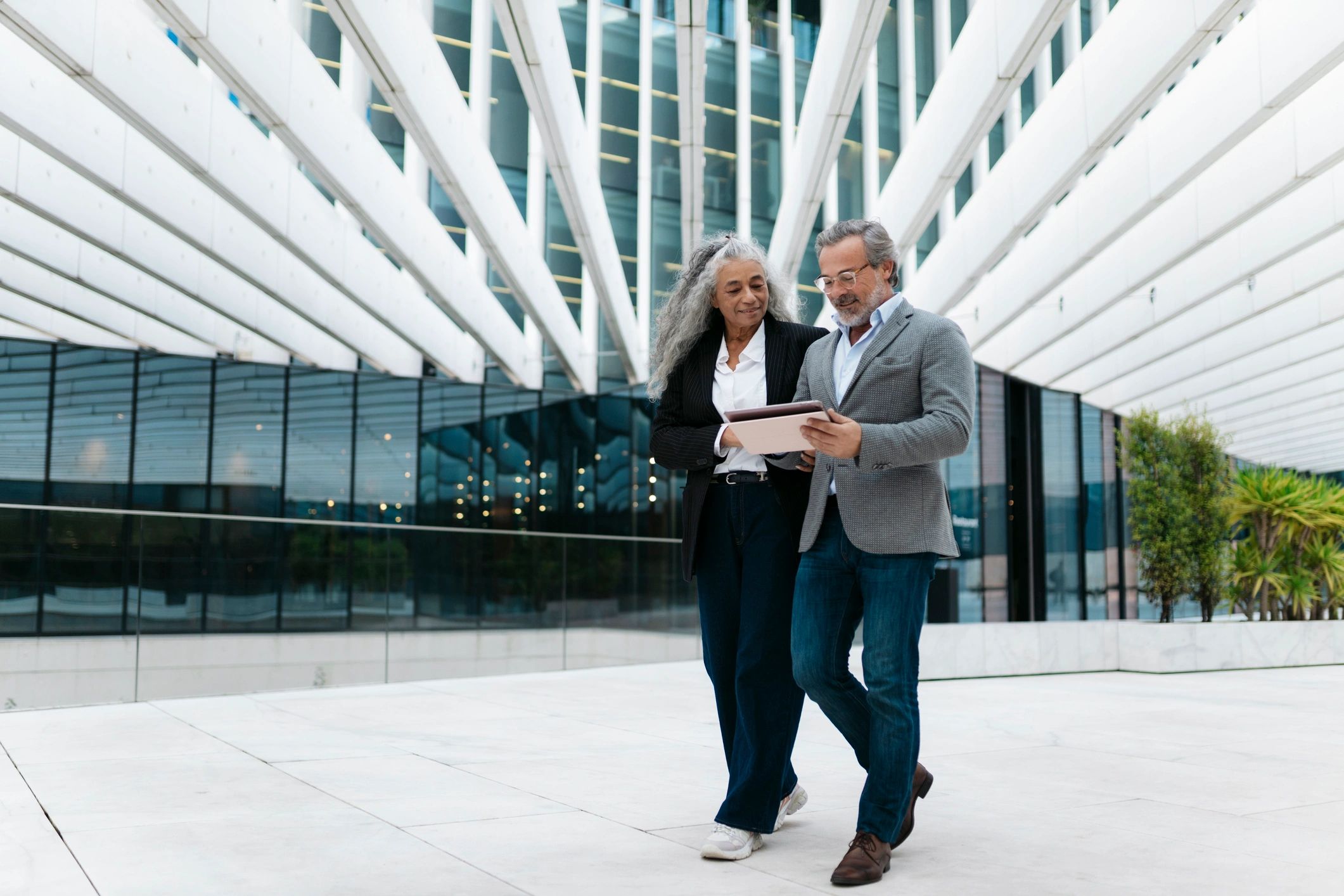 Two professionals reviewing a tablet outside a modern building.