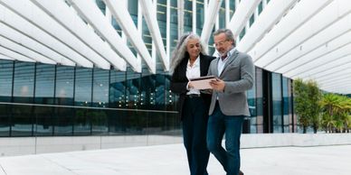Two professionals reviewing a tablet in a modern outdoor setting.