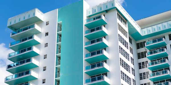 Modern white and teal apartment building under a clear blue sky.