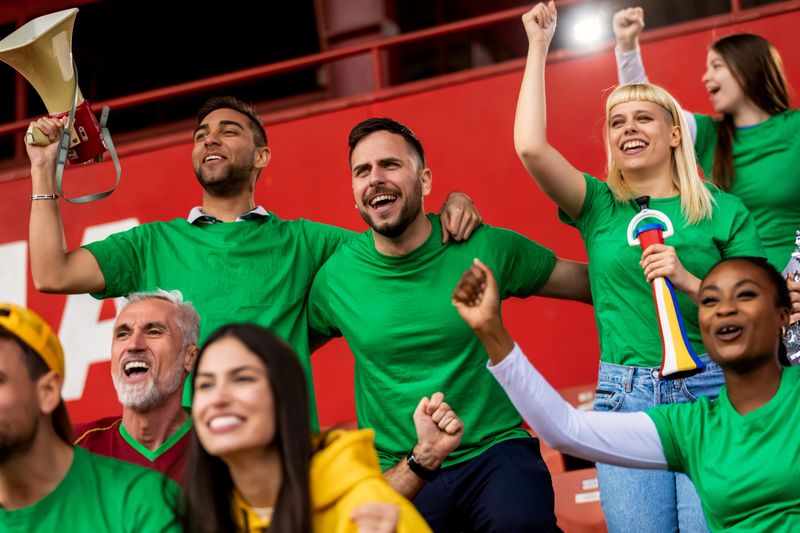 Football, soccer fans are cheering for their team at the stadium on the match.
