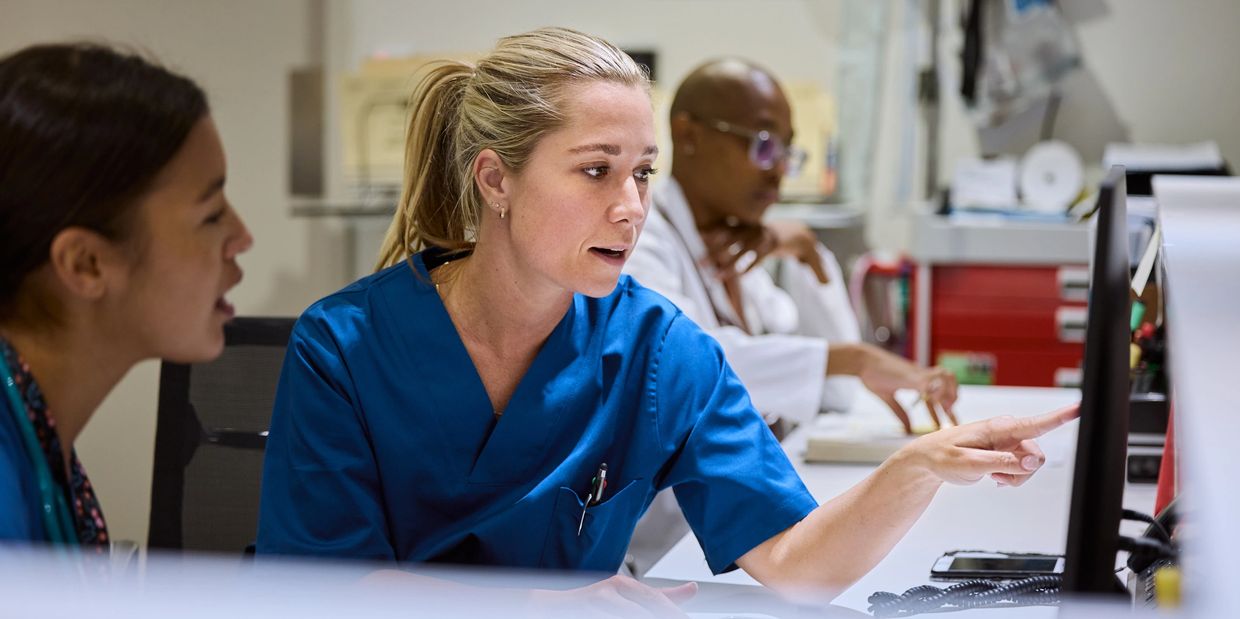 Medical professionals collaborating over a computer in a clinical setting.
