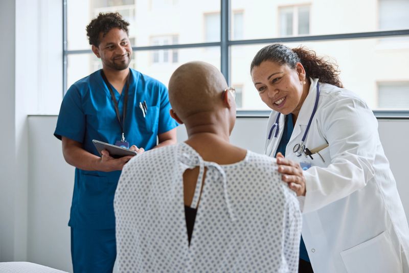 Smiling female doctor encouraging patient during consultation. Smiling medical staff is consoling woman. They are wearing uniforms.