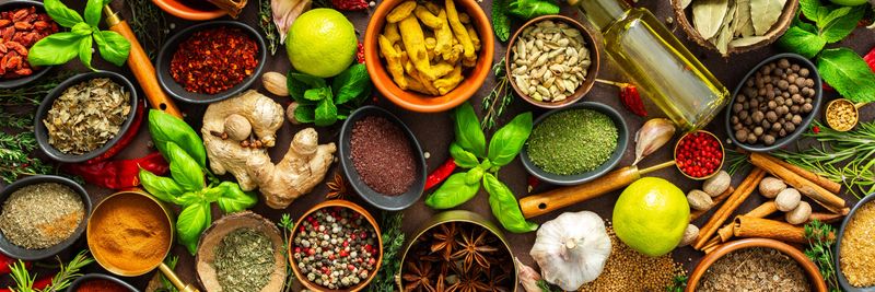 A visually striking arrangement of fresh spices and herbs on a brown surface, highlighting their vivid colors, intricate details and rich culinary essence, banner