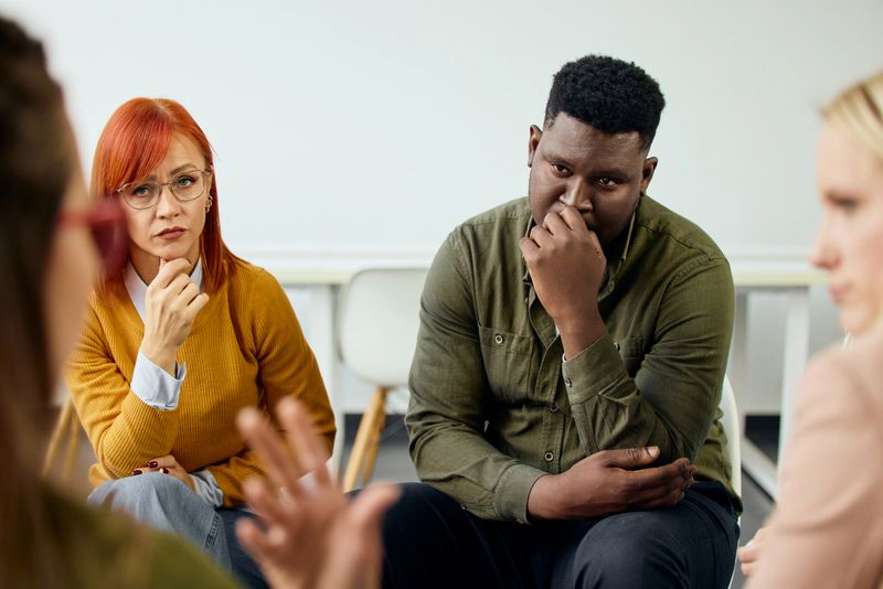 Group of individuals seated together attentively listening and participating in conversation.