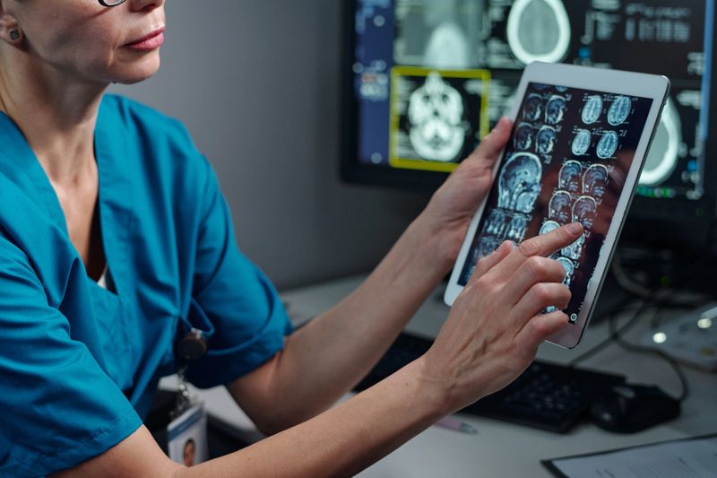 Medical professional analyzing brain scans on tablet device in modern medical facility. Checking patient data and interpreting MRI results for diagnosing conditions
