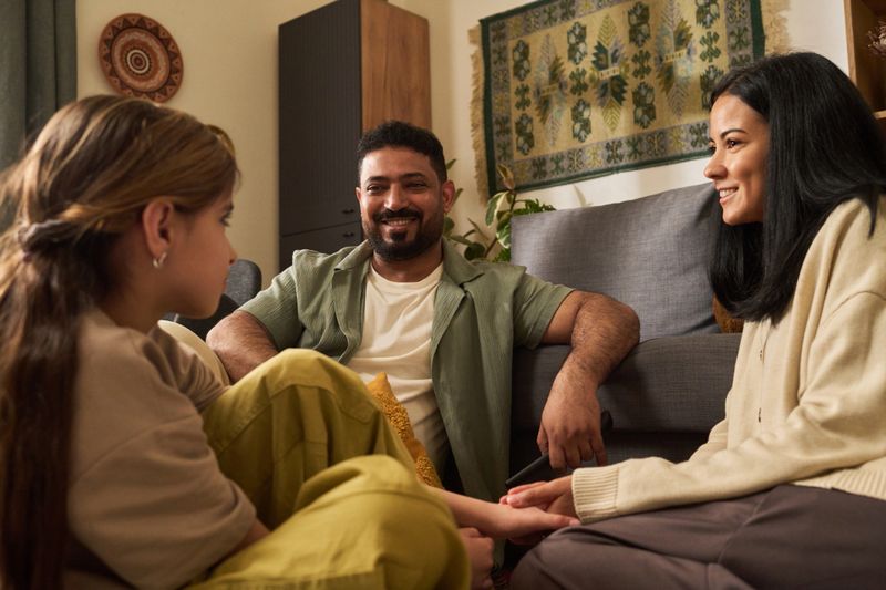 Happy family enjoying quality time in warm living room, smiling and interacting with each other on comfortable couch in cozy environment preparing for evening activities